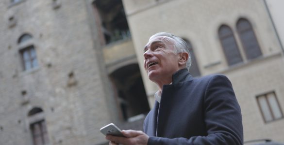 elegant senior man browsing smartphone on city street